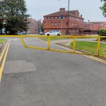 Access road secured with a closed yellow metal gate